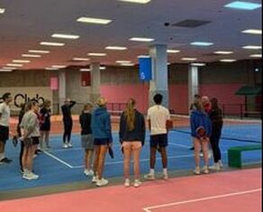 NCCP Level 1 training Group of people standing on indoor pickleball courts listening to an instructor during training session