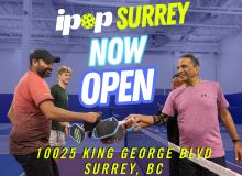 Four men in a warehouse exchanging a black helmet with text overlay about ipop Surrey opening at King George Blvd.